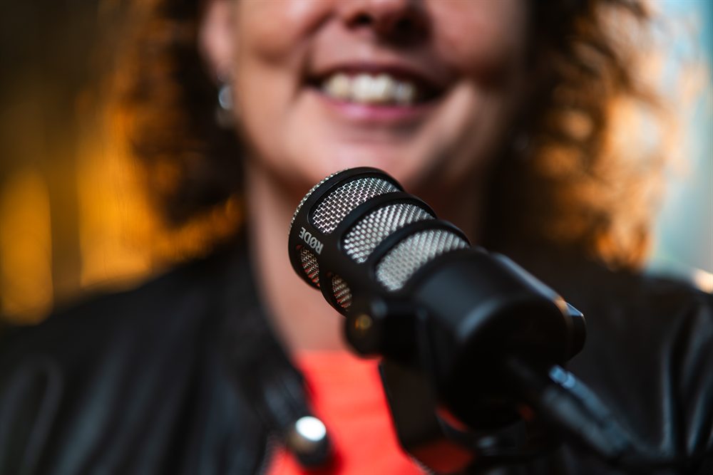 The microphone during a podcast recording, Zanna smiling behind it
